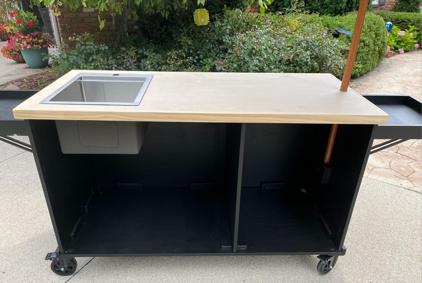 Black coffee cart with a stainless drop-in sink, a warm wood top and a parasol umbrella