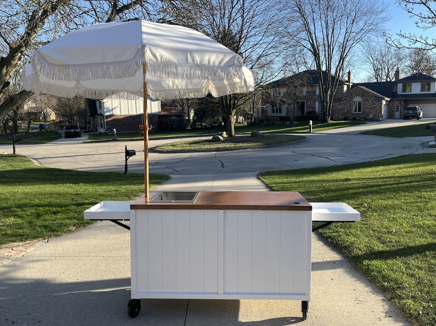 White coffee and espresso cart with a vertical shiplap front, a rich brown wood top and a parasol umbrella