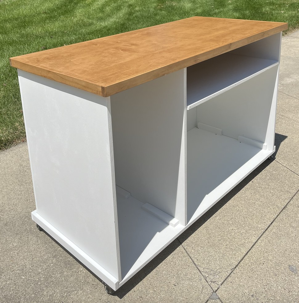 White cart with a warm natural wood top and open storage with a divider shelf, on casters