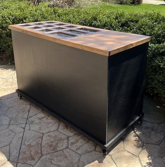 Black cart with a deep brown wood top and acrylic food wells